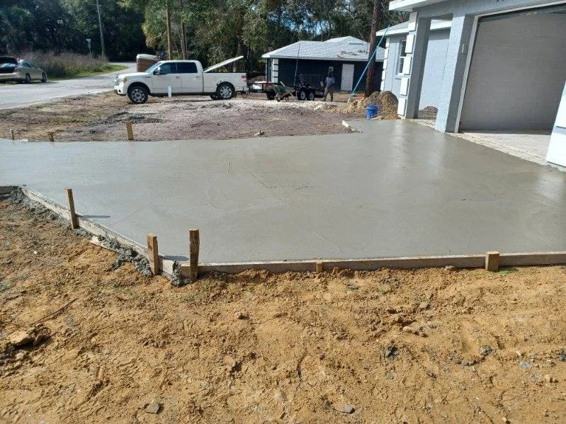 Newly poured concrete pad with wooden forms and gravel base at residential property
