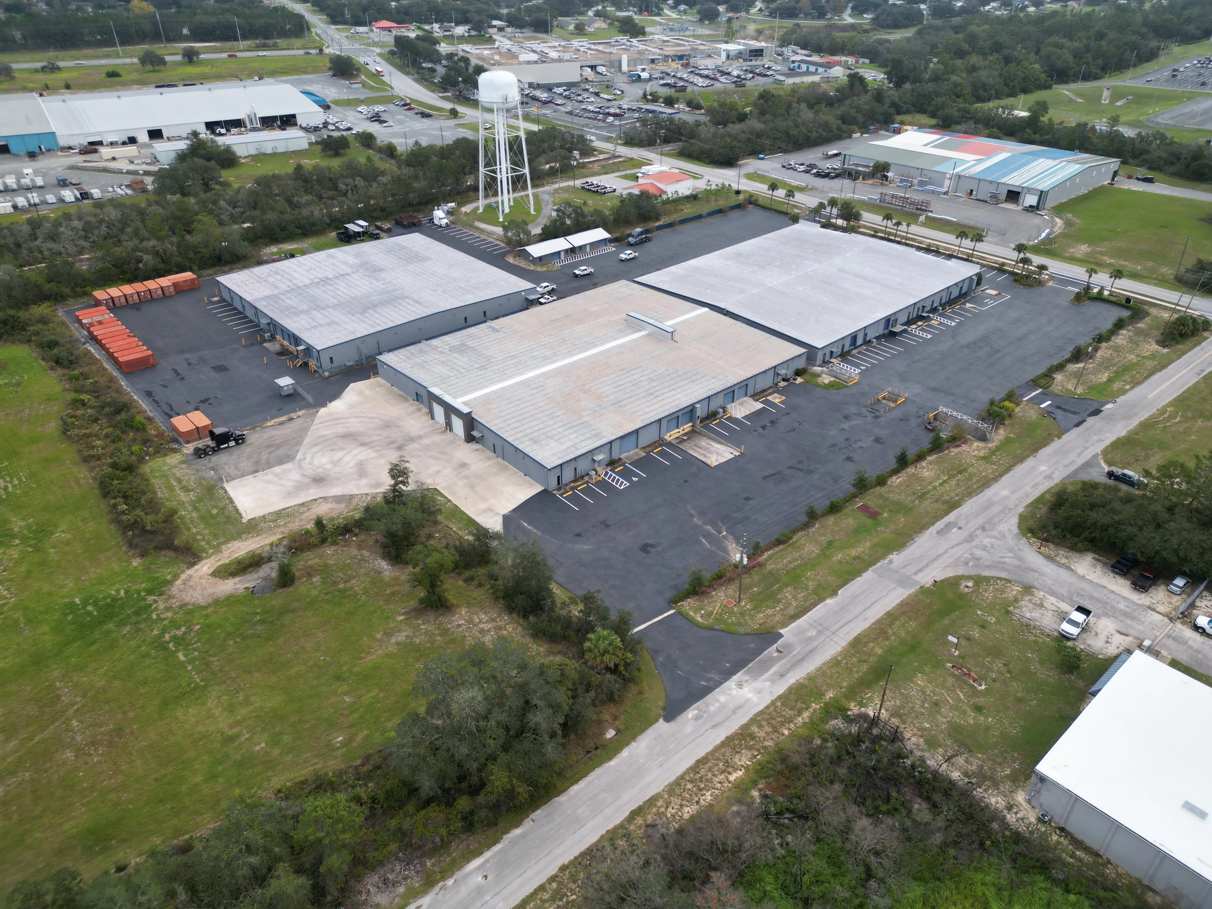 Aerial view of newly paved commercial parking lots with three warehouse buildings and marked parking spaces