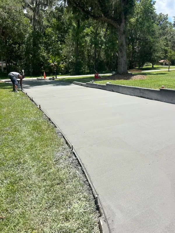Newly paved asphalt driveway with metal edging and manicured lawn borders