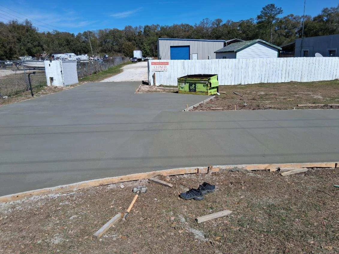 Newly paved asphalt driveway with wooden forms and graded edges at commercial property