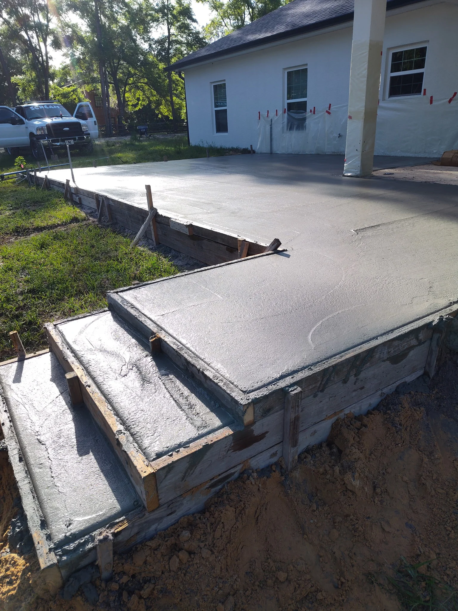 Newly poured concrete driveway sections with wooden forms and grading stakes