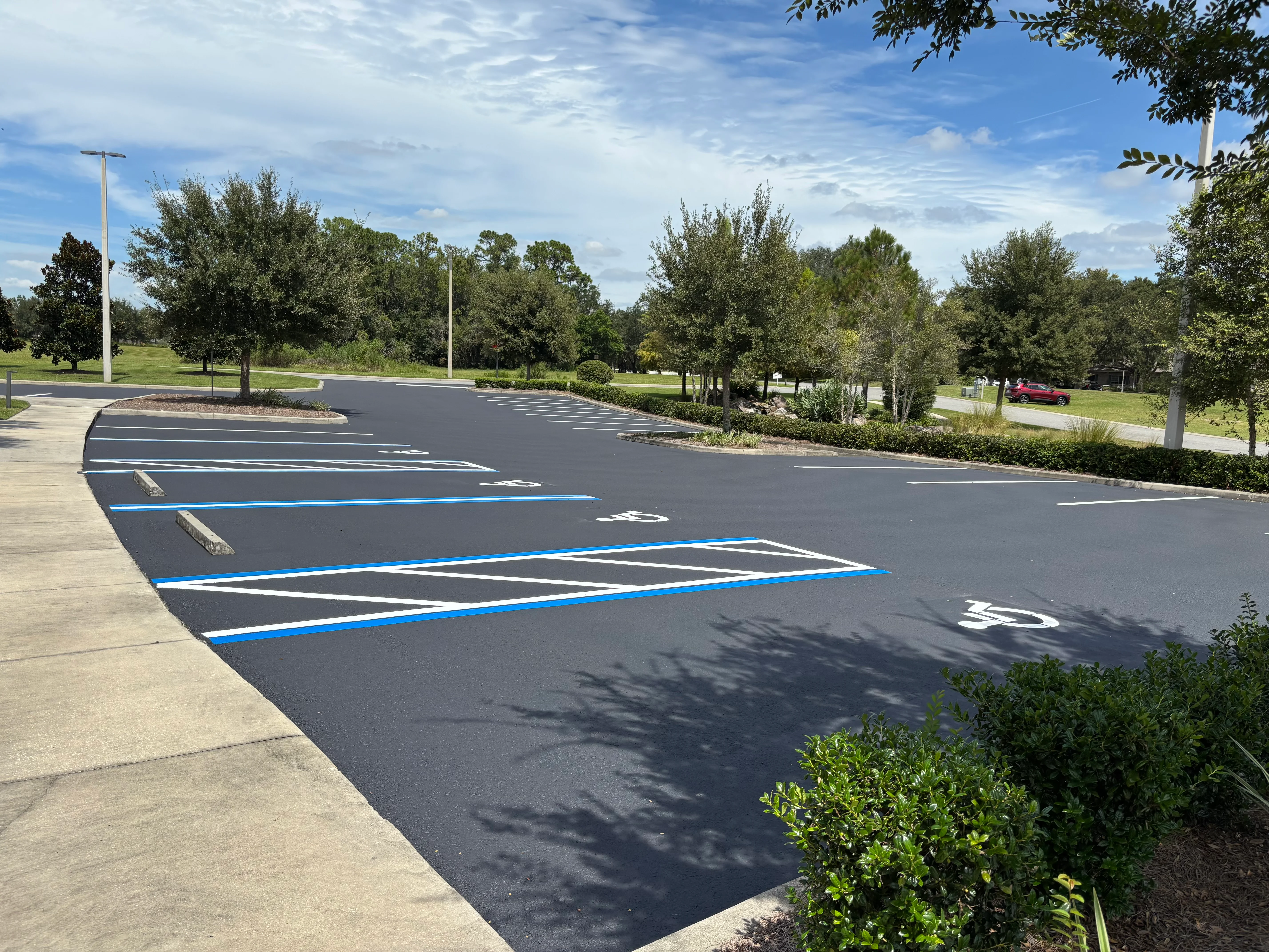 New asphalt parking lot with blue-lined ADA accessible spaces and white directional markings