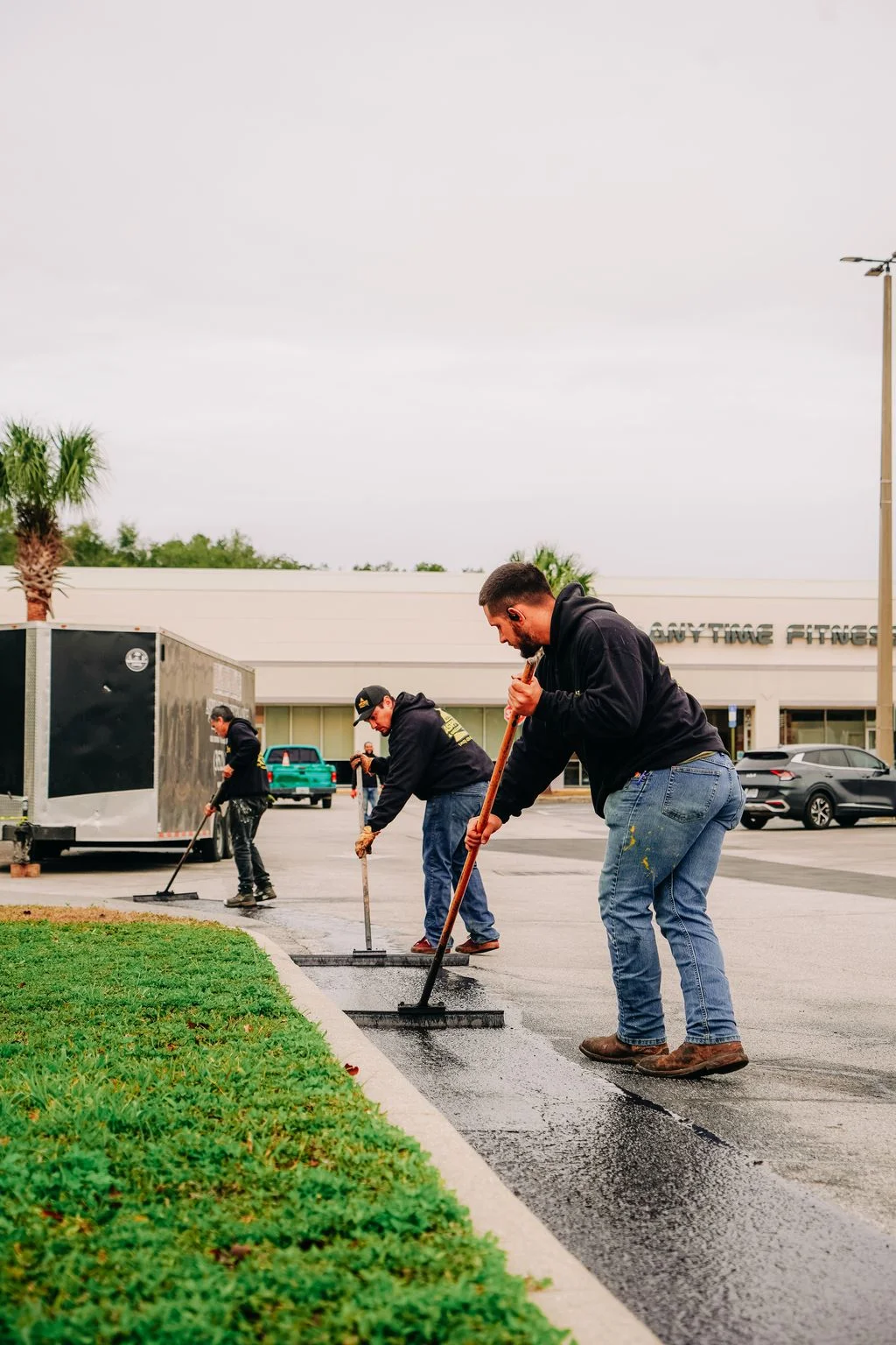 Crew applying sealcoat to commercial parking lot with squeegee tools