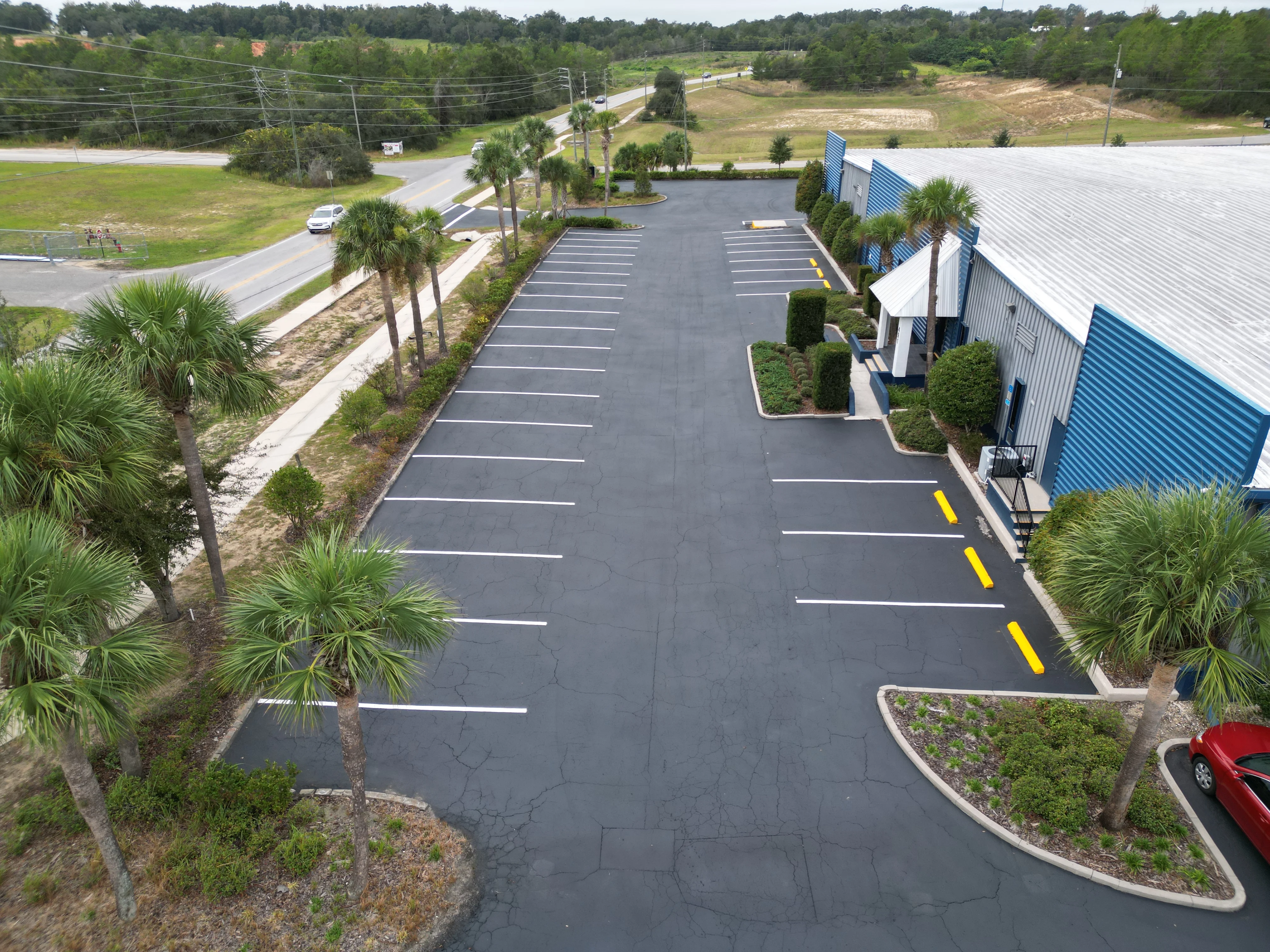 Aerial view of newly paved commercial parking lot with white and yellow striping and landscaping