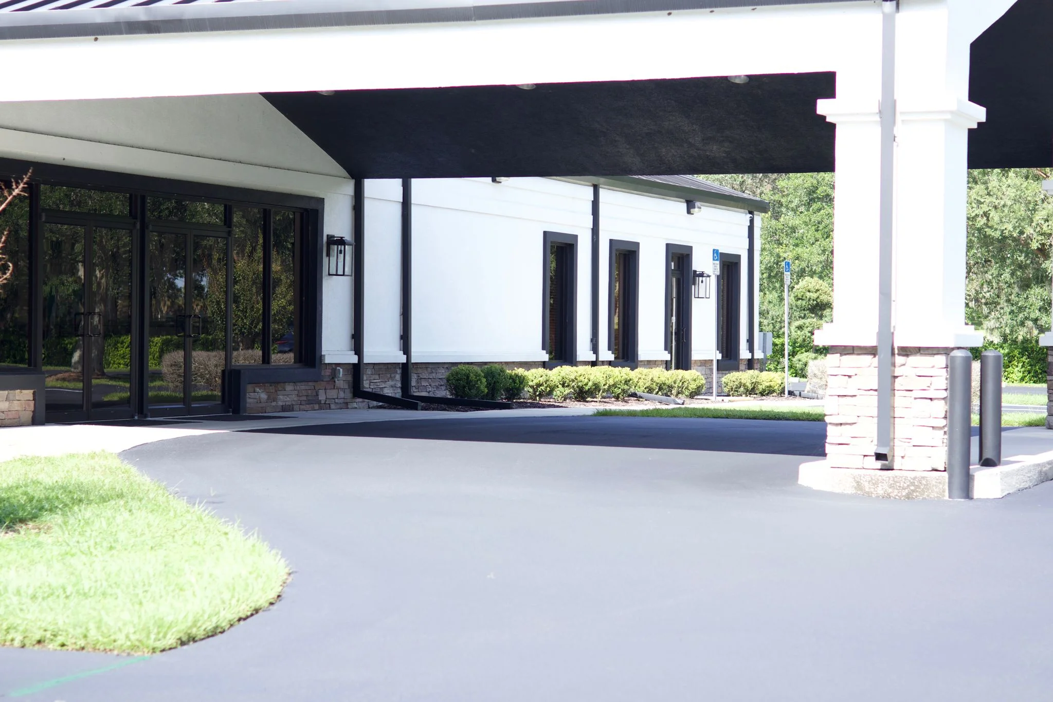 Newly paved dark asphalt entrance apron with curved edges at commercial building