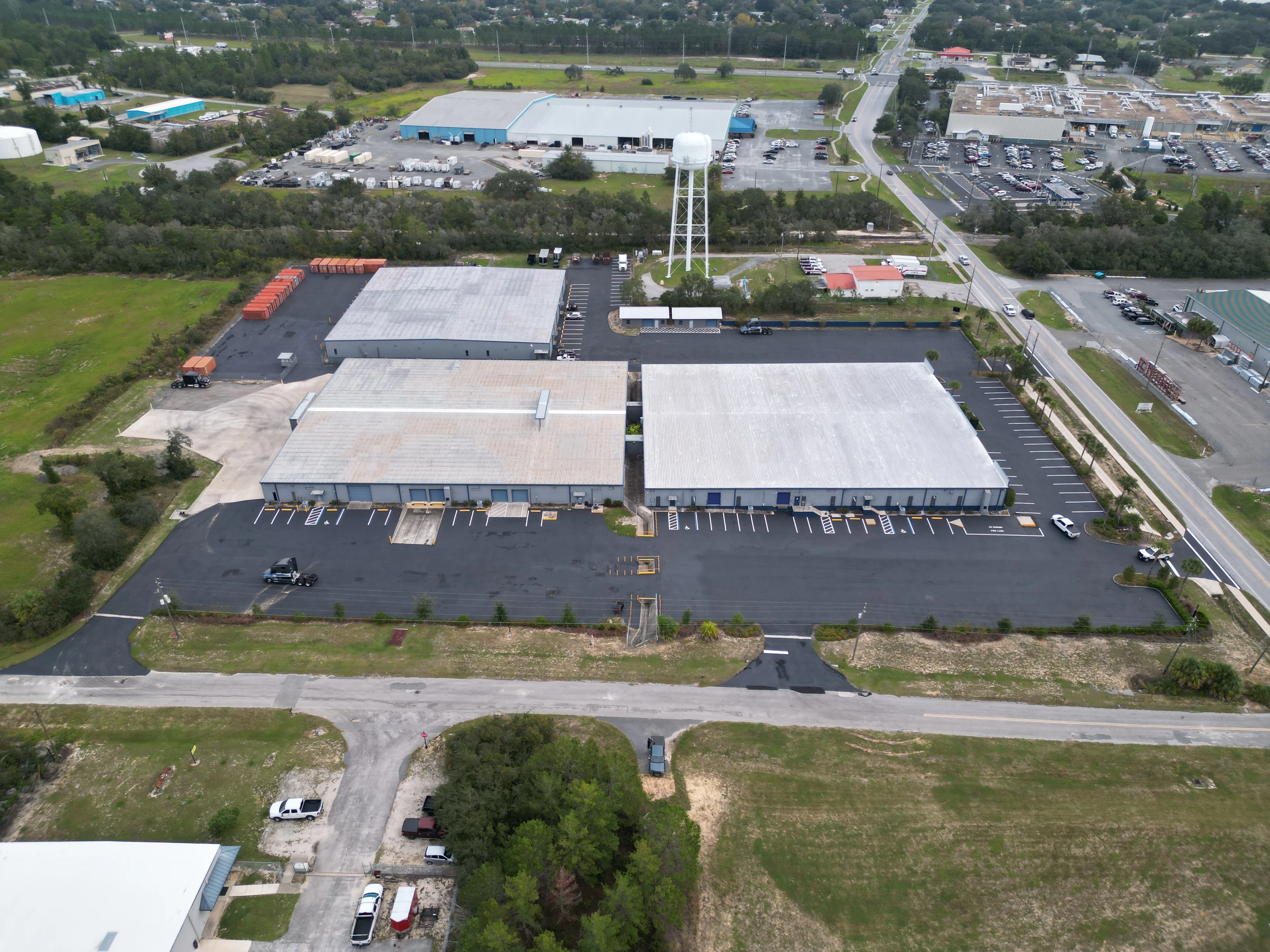Aerial view of newly paved commercial parking lot with two retail buildings and organized parking spaces