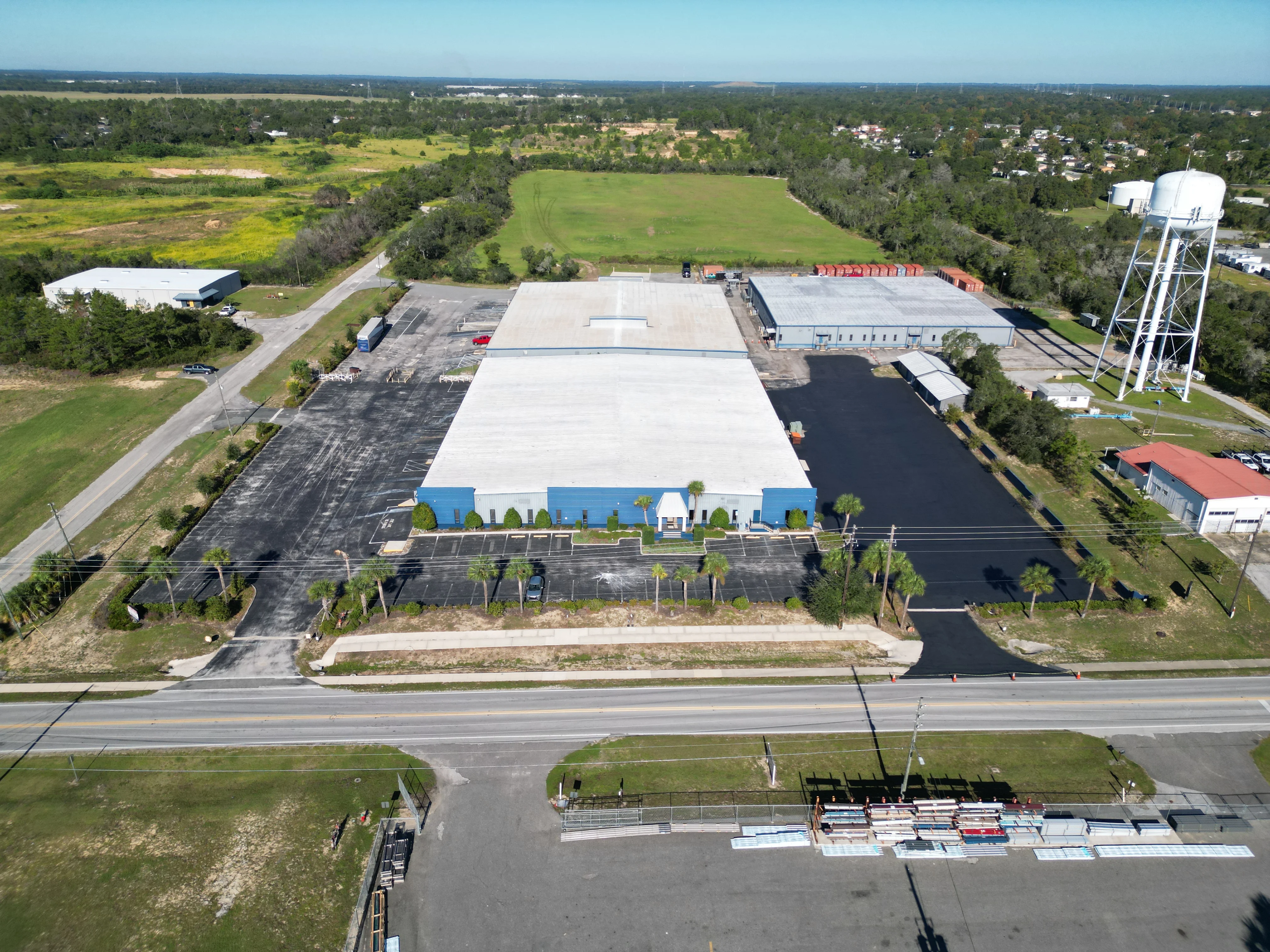 Aerial view of newly paved commercial parking lot with white roof building and landscaping