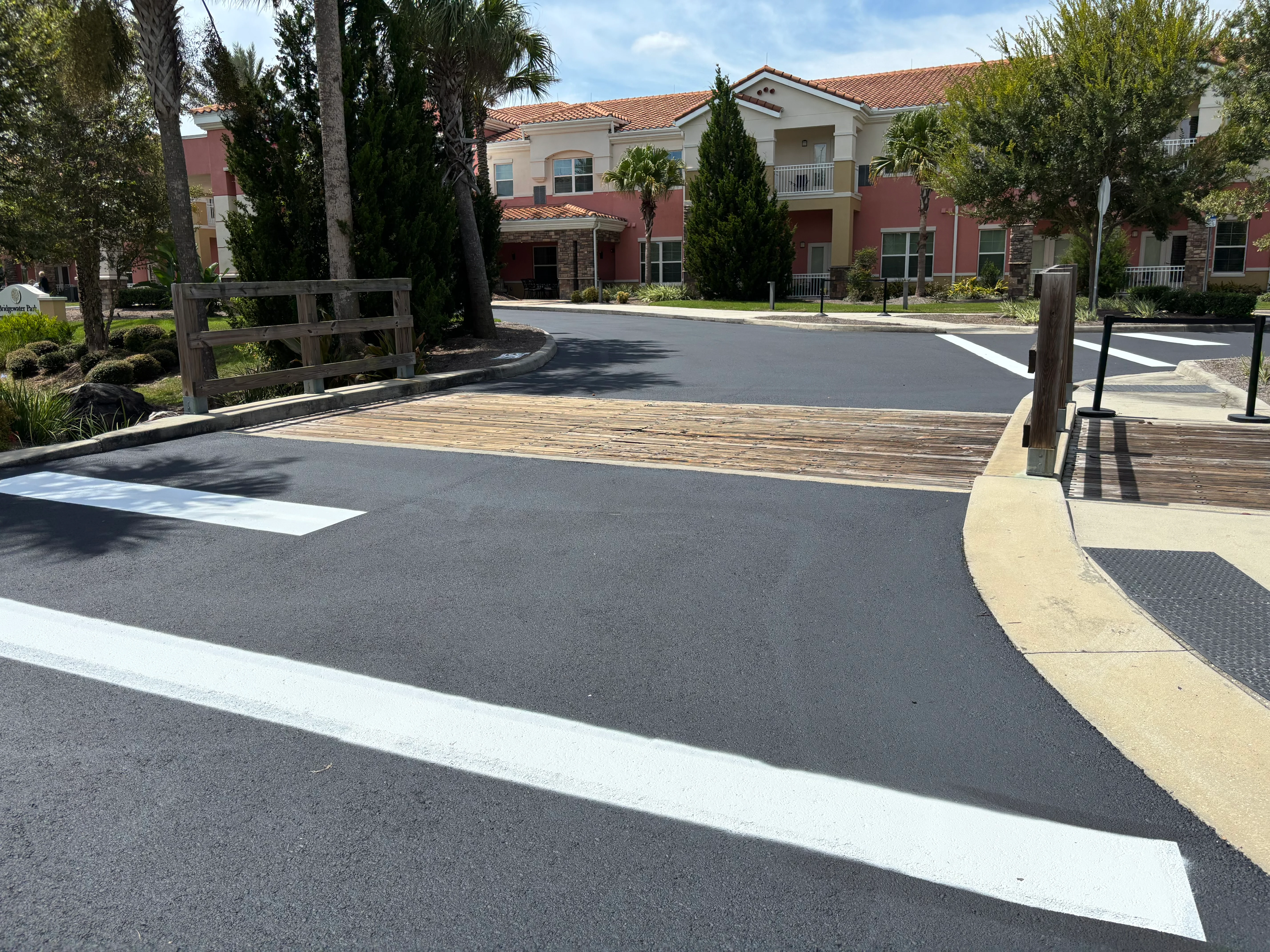 Newly paved asphalt driveway with white striping at residential community entrance in Ocala
